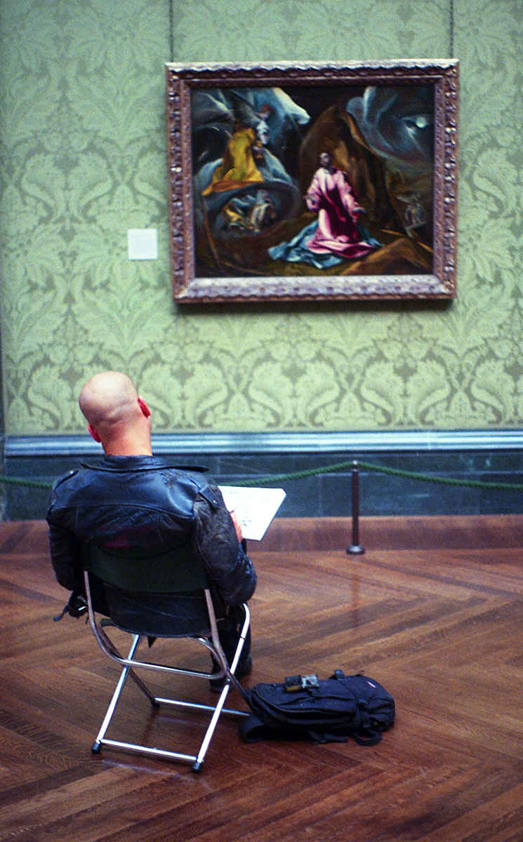 Man artist in gallery copying studying old master artwork in seat