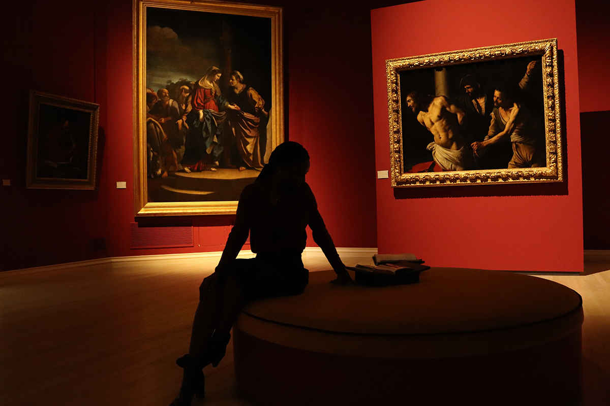 Woman sitting in art gallery looking at art paintings renaissance red walls photo
